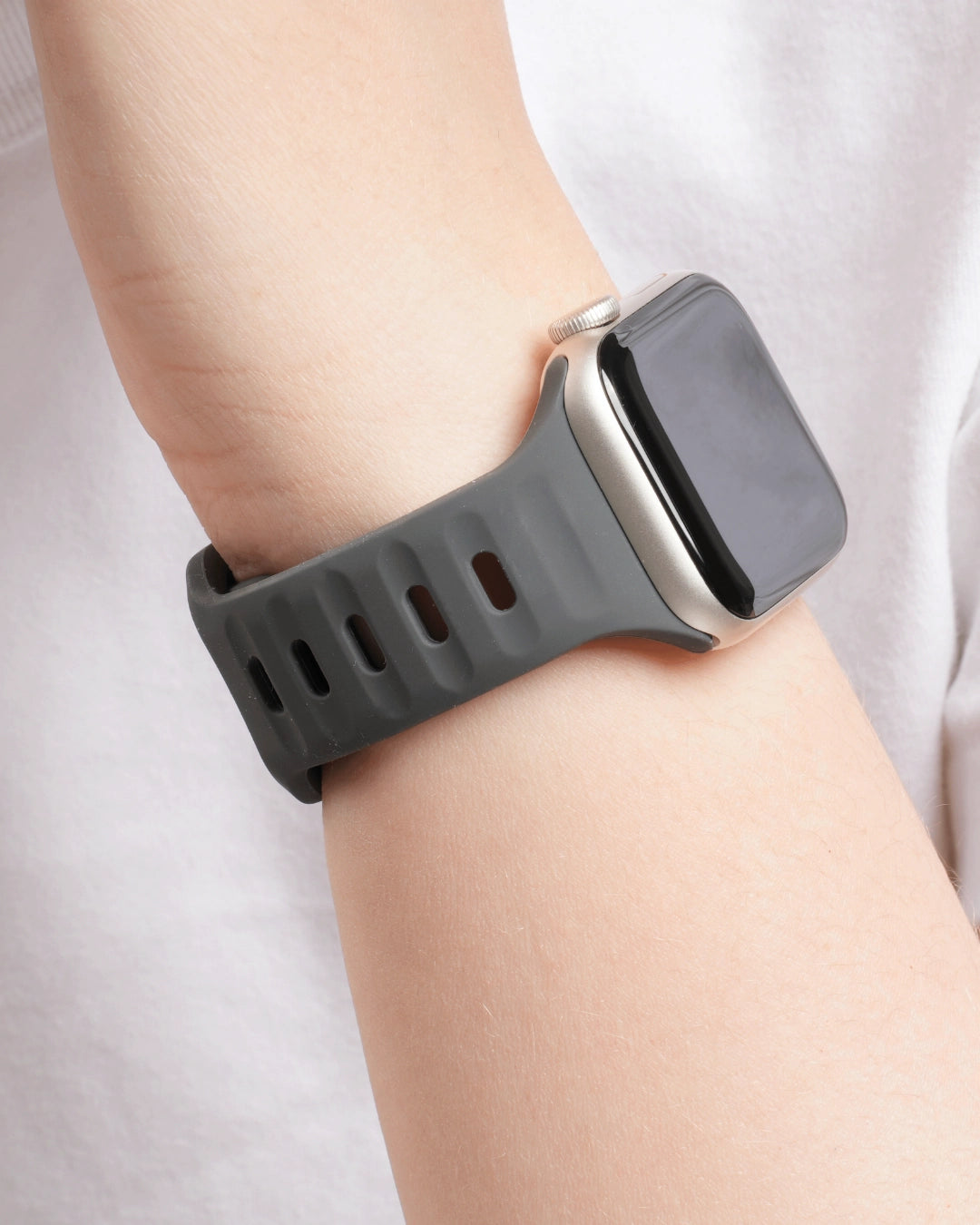 Sportliches Silikonarmband in Dunkelgrau für Apple Watch am Handgelenk einer Person in weißem Shirt