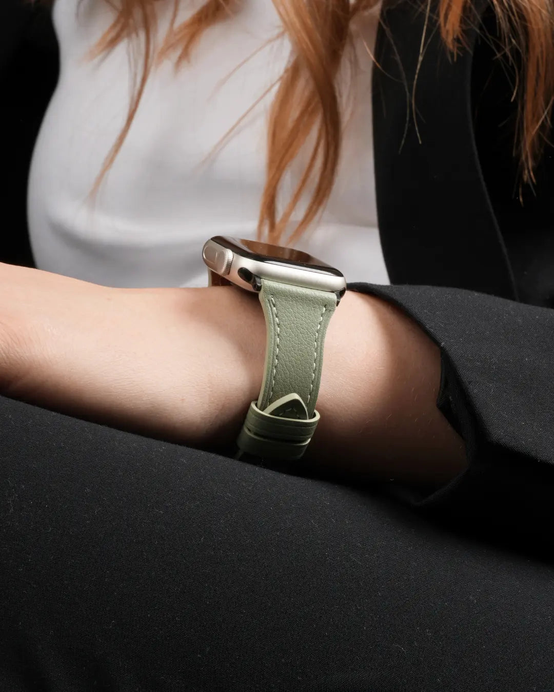 Apple Watch mit olivgrünem Lederarmband am Handgelenk einer Person im schwarzen Blazer