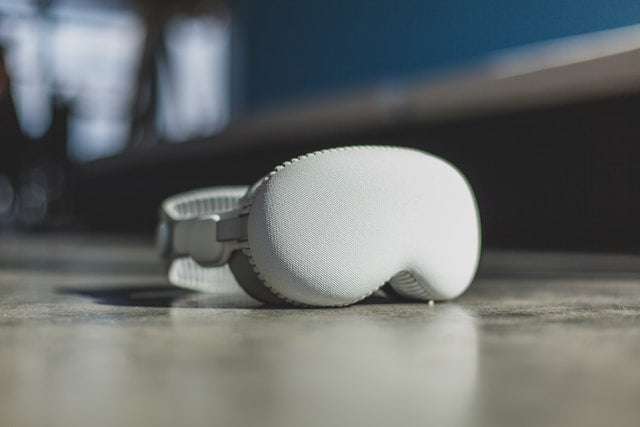 Apple Vision Pro Hülle in Grau auf einem Tisch liegend, mit unscharfem Hintergrund.