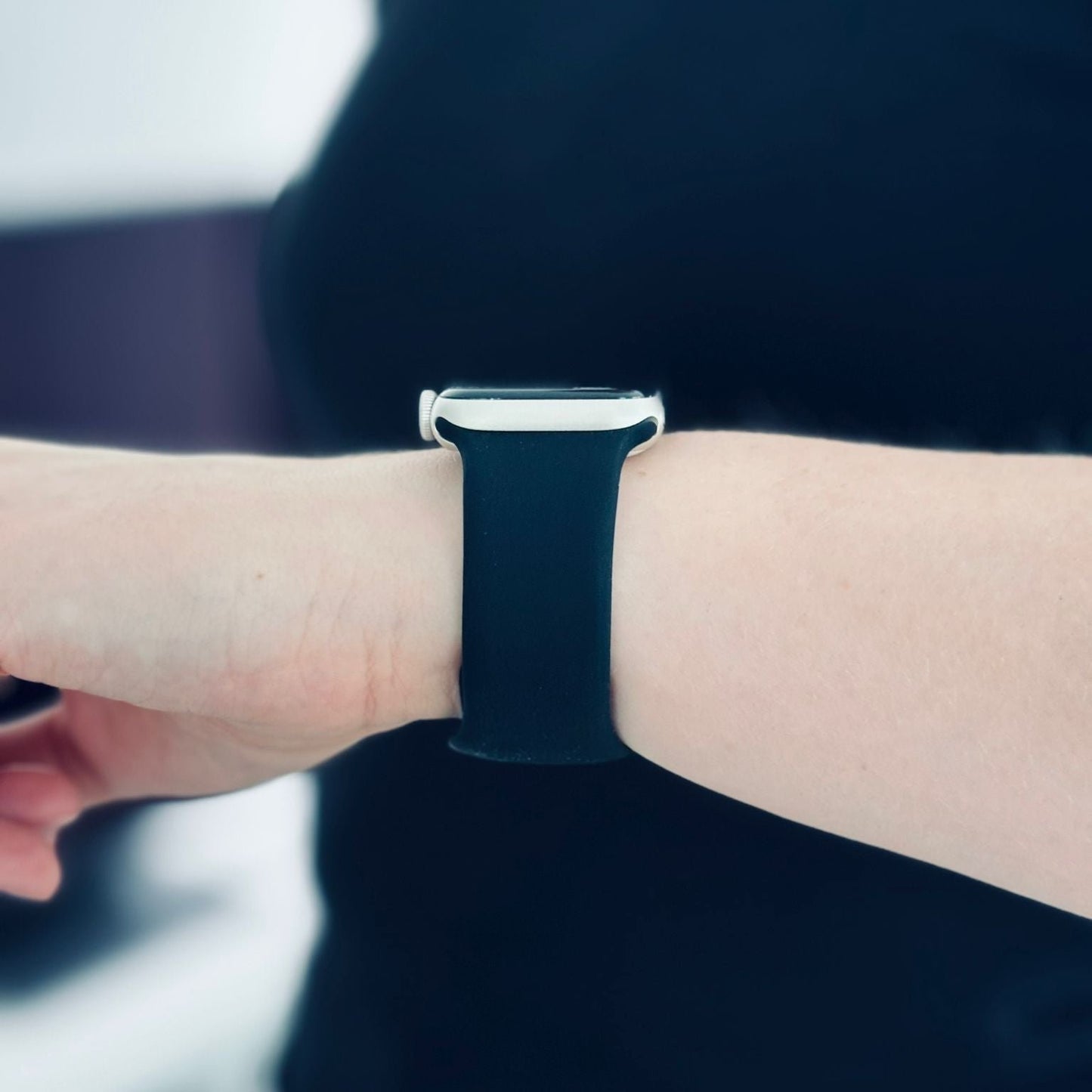 Apple Watch mit schwarzem Silikonarmband am Handgelenk einer Person