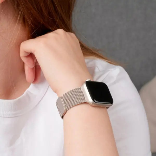 Apple Watch mit silbernem Milanaise-Armband am Handgelenk einer Person in weißem Shirt